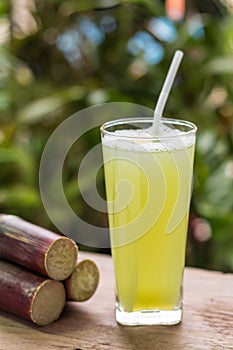 Sugarcane juice with piece of sugarcane on wooden background