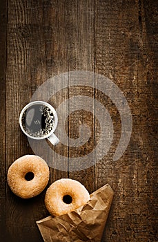 Sugared doughnuts and coffee on rustic wood