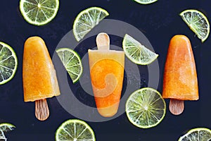 Sugarless orange popsicles with lime slices. Healthy dessert