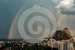 Sugarloaf Mountain and Guanabara Bay under a cloudy sky with a rainbow in Rio de Janeiro, Brazil