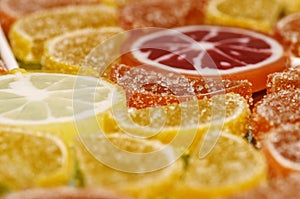 Sugary marmalade like lemon and orange slices with lollipops. Closeup macro candy background