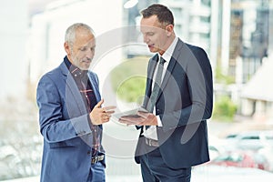 Suggesting some ideas to each other. two businessmen working on a digital tablet together in a modern office.