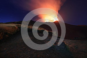 Suggestiva eruzione del vulcano Etna con esplosione di lava dalla cima del cratere con sfondo il cielo stellato e paesaggio photo