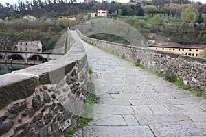 The suggestive and famous Ponte del Diavolo of Lucca built in bricks over a river in an ancient medieval village in Borgo a