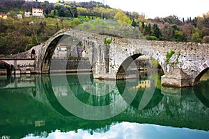 The suggestive and famous Ponte del Diavolo of Lucca built in bricks over a river in an ancient medieval village in Borgo a