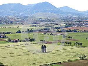 suggestive view from above of the cultivated fields with regular geometric shapes in the plain with the mountains