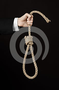 Suicide and business topic: Hand of a businessman in a black jacket holding a loop of rope for hanging on black isolated