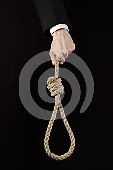 Suicide and business topic: Hand of a businessman in a black jacket holding a loop of rope for hanging on black isolated