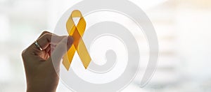 Suicide prevention and Childhood Cancer Awareness, Yellow Ribbon on wooden background  for supporting people living and illness.