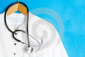 Suit Doctor's with a stethoscope on a hanger. Doctor's coat on a blue background. Ad space, copyspace, medical template