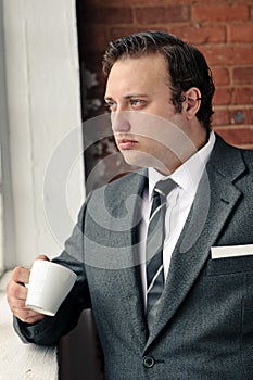 Suit man drinks coffee and thinks