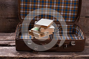 Suitcase with books on the old boards.