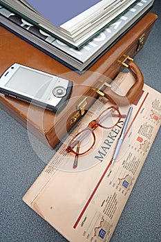 Suitcase with financial newspaper and PDA