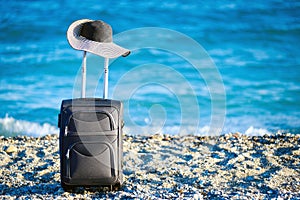 Suitcase and hat on beach