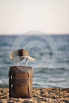 Suitcase and hat on beach