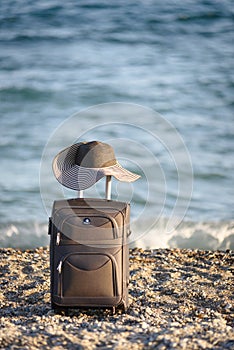 Suitcase and hat on beach