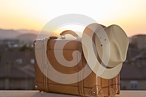 Suitcase and hat at sunset, allusion to travel, beginning of vacation