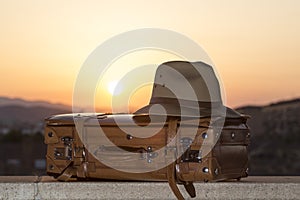 Suitcase and hat at sunset, allusion to travel, beginning of vacation