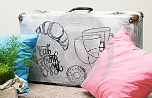Suitcase with an inscription. Phrase Eat, Drink, Enjoy. Brush Pen lettering with pillow and plants like a cozy decoration