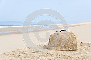 Suitcase made out of sand on beach