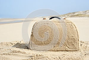 Suitcase made out of sand on beach