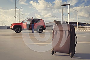 Suitcase in an open parking lot against the background of a car close-up