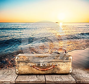 Suitcase with sunglasses on wooden pier