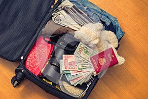 Suitcase with things teddy bear and a foreign passport. Asian money and hundred-dollar bills for travel. Concept