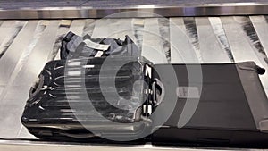 Suitcases on a rotating conveyor belt in an airport wait for their owners