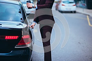 Suited businessmen opening the back door of his limo