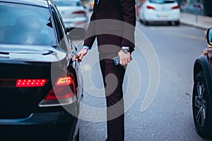 Suited businessmen opening the back door of his limo