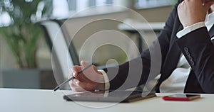 A suited director in a business office employs a pen to contemplate new business ventures, exemplifying strategic