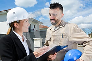 suited woman on worksite talking to contractor