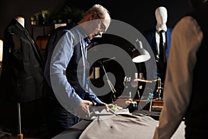 Suitmaker manufacturing suit in tailoring studio photo