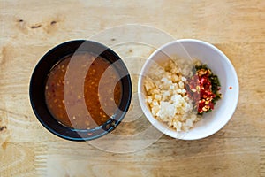 Sukiyaki dipping sauce with minced garlic and chilli in black bowl