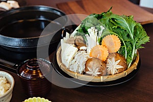 Sukiyaki vegetables set including cabbage, false pak choi, carrot, shiitake, enokitake and tofu in bamboo basket