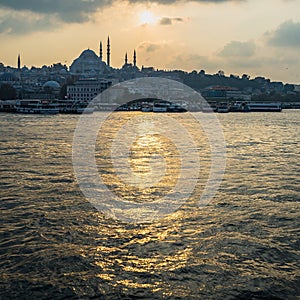 Suleymaniye Mosque surrounded by buildings and the sea during the sunset in Istanbul in Turkey