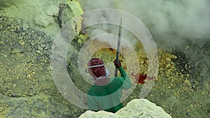 Sulfur miner extracting sulfur at solfatara inside the crater of Kawah Ijen volcano in East Java, Indonesia