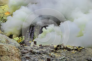 Sulfur mining operation in Mount Ijen, Indonesia. Toxic gas escaping from volcanic vents. Pipes to divert the gas for condensing t photo