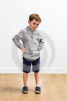 Sulking conflicted boy standing with hands on hips expressing attitude