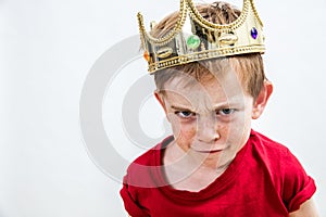 Sulking funny face of a little boy wearing a crown