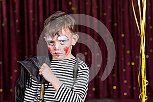 Sulky little boy wearing face paint on stage