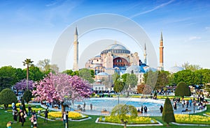 Sultanahmet district in Istanbul, Turkey. Walking people, green grass fields and fountain near famous landmark Hagia Sophia. photo