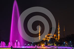 Sultanahmet Square with the Blue Mosque and an illuminated fountain in the night in Istanbul