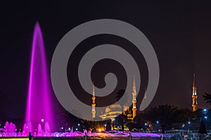 Sultanahmet Square with the Blue Mosque and an illuminated fountain in the night in Istanbul