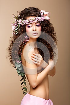 Sultry Beauty. Attractive Naked Woman with Long Curly Hair and Wreath of Flowers