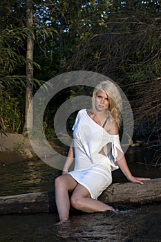 Sultry blonde woman sitting in river