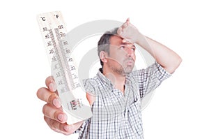 Sumer heat and heatwave concept with man holding thermometer photo