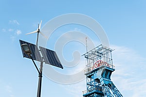 Summary of new and old technologies of energy production. Street lamp with a photovoltaic panel, a windmill and an old mine shaft