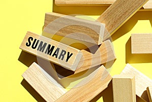 The SUMMARY text is written on one of the many scattered wooden blocks, against a yellow background.